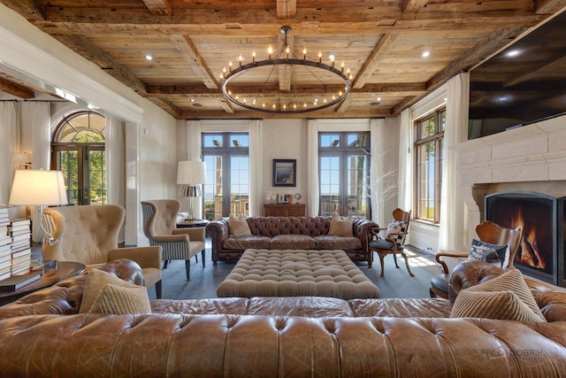 living room featuring an inviting chandelier, a premium fireplace, beam ceiling, and french doors