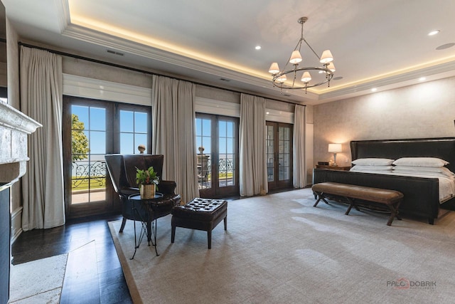 bedroom with access to exterior, a tray ceiling, and multiple windows