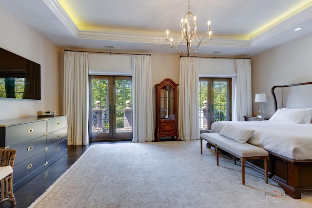 bedroom featuring french doors, a chandelier, ornamental molding, a tray ceiling, and access to exterior