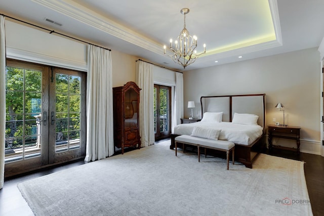 bedroom with french doors, an inviting chandelier, access to outside, a tray ceiling, and hardwood / wood-style flooring