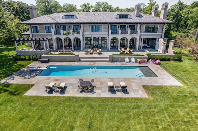 rear view of property with a yard, a fire pit, a patio, and a balcony