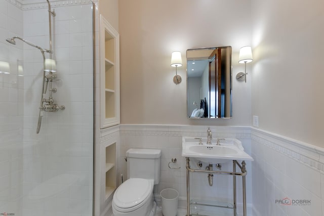 bathroom featuring tiled shower, sink, tile walls, and toilet