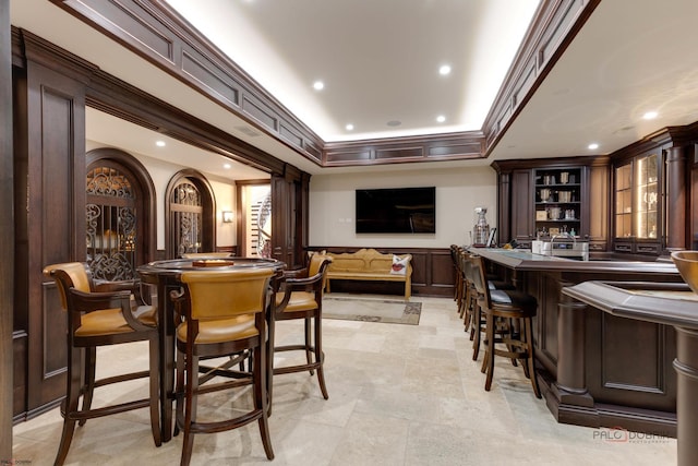 bar with a raised ceiling, crown molding, and dark brown cabinets