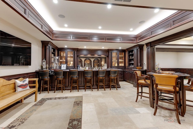 bar with ornamental molding, dark brown cabinets, and ornate columns