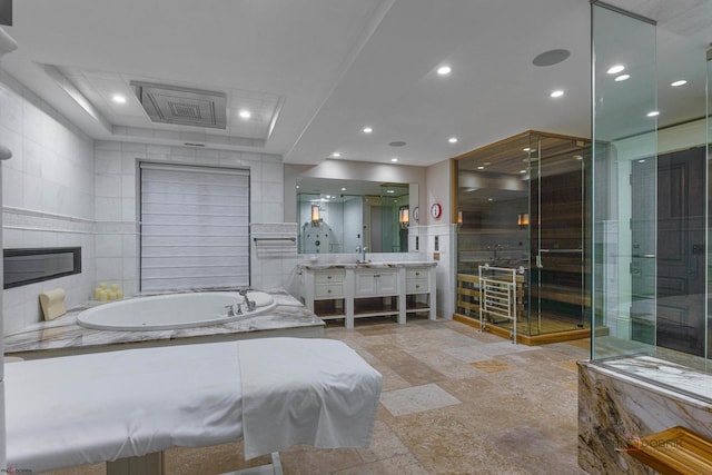 bathroom with independent shower and bath, vanity, tile walls, and a fireplace