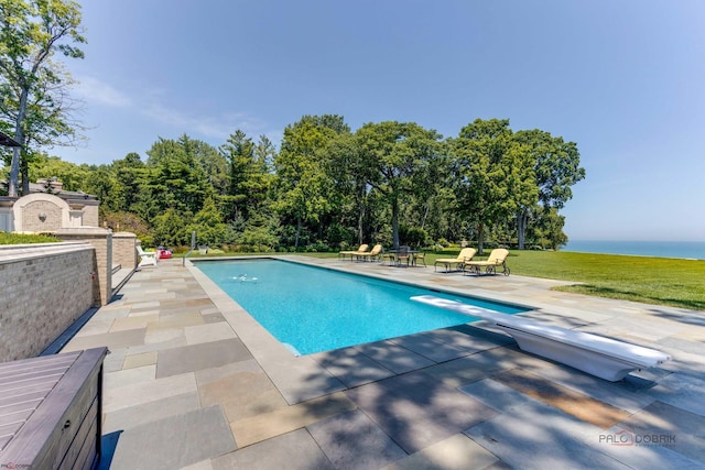 view of pool with a patio, a yard, and a diving board