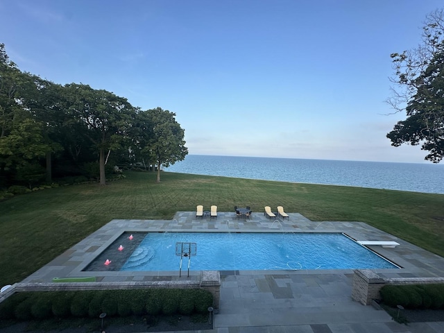 view of pool featuring a water view, a diving board, a patio area, and a lawn