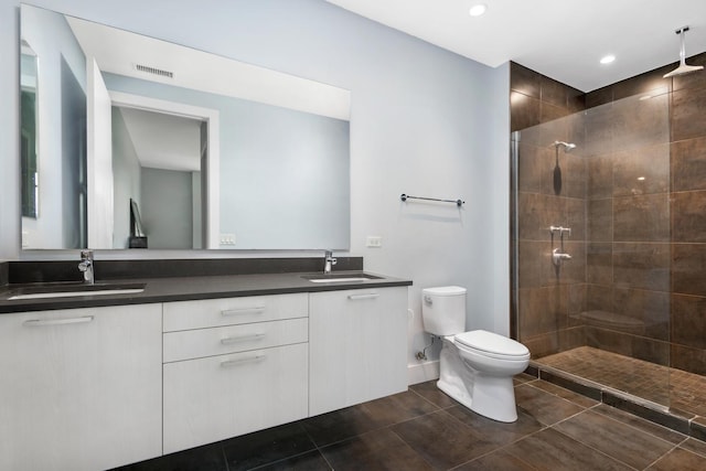 bathroom with tiled shower, vanity, and toilet