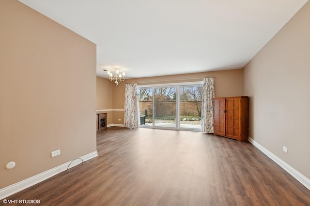 unfurnished living room featuring an inviting chandelier and dark hardwood / wood-style floors