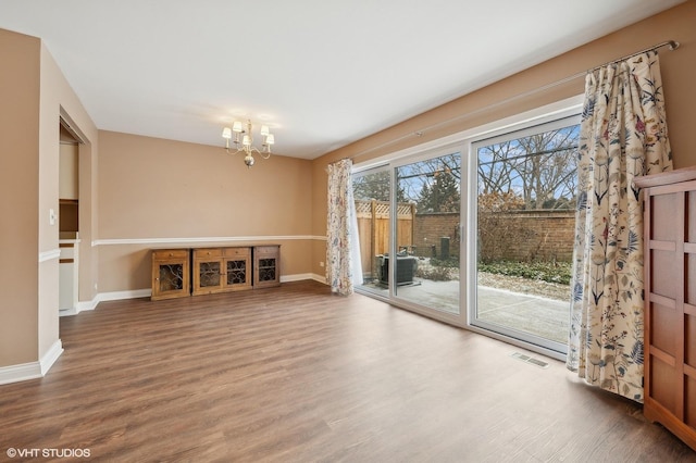 unfurnished living room featuring wood-type flooring and a chandelier