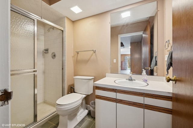 bathroom featuring walk in shower, vanity, toilet, and tile patterned flooring