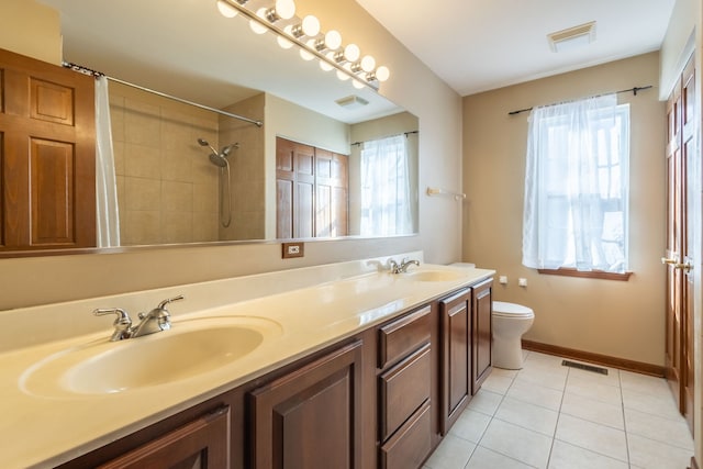 bathroom featuring vanity, a wealth of natural light, tile patterned floors, and toilet