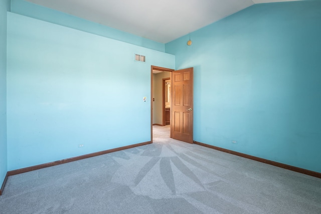 carpeted spare room featuring vaulted ceiling