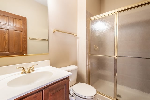 bathroom with vanity, a shower with shower door, and toilet