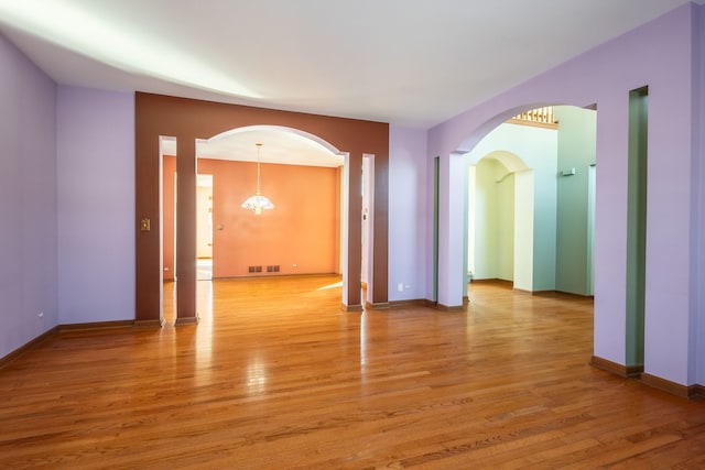 unfurnished room featuring hardwood / wood-style flooring and a chandelier