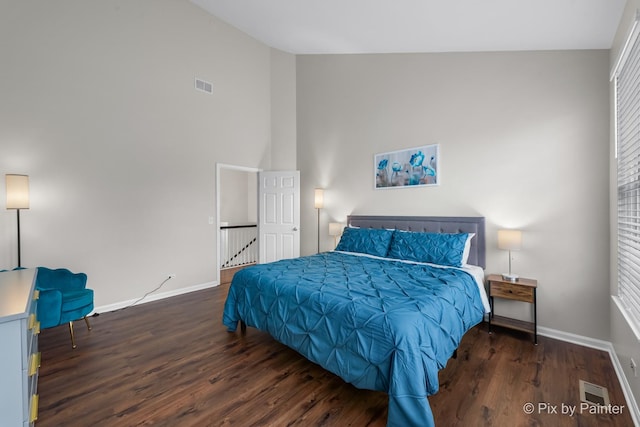 bedroom with high vaulted ceiling and dark wood-type flooring