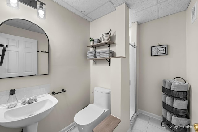 bathroom with toilet, a paneled ceiling, tile patterned floors, and sink