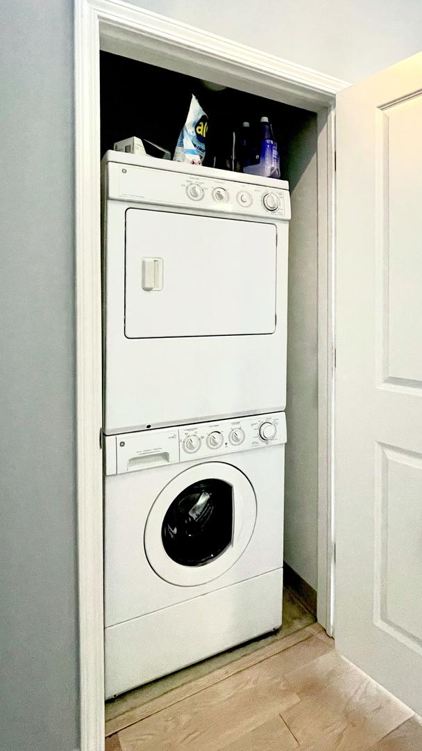 laundry room featuring stacked washer and dryer and light wood-type flooring