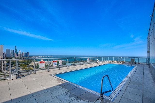 view of pool featuring a water view and a patio