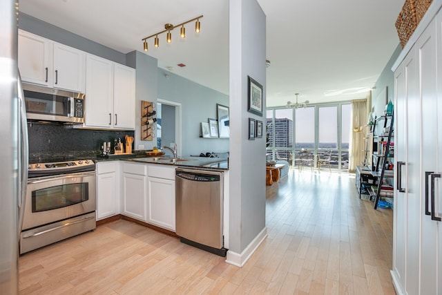 kitchen featuring white cabinets, appliances with stainless steel finishes, expansive windows, and light wood-type flooring