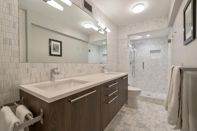 bathroom featuring toilet, vanity, tile walls, and a shower with door