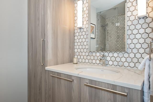 bathroom with decorative backsplash, a tile shower, and vanity