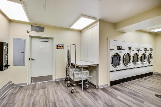 laundry area with light hardwood / wood-style flooring, a baseboard heating unit, separate washer and dryer, and electric panel