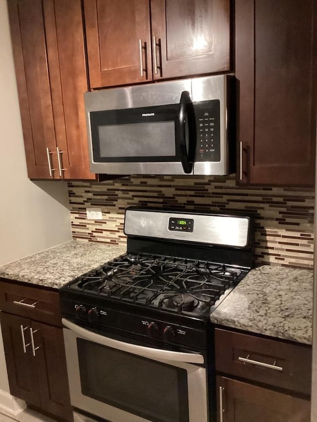 kitchen with light stone counters, dark brown cabinetry, stainless steel appliances, and tasteful backsplash