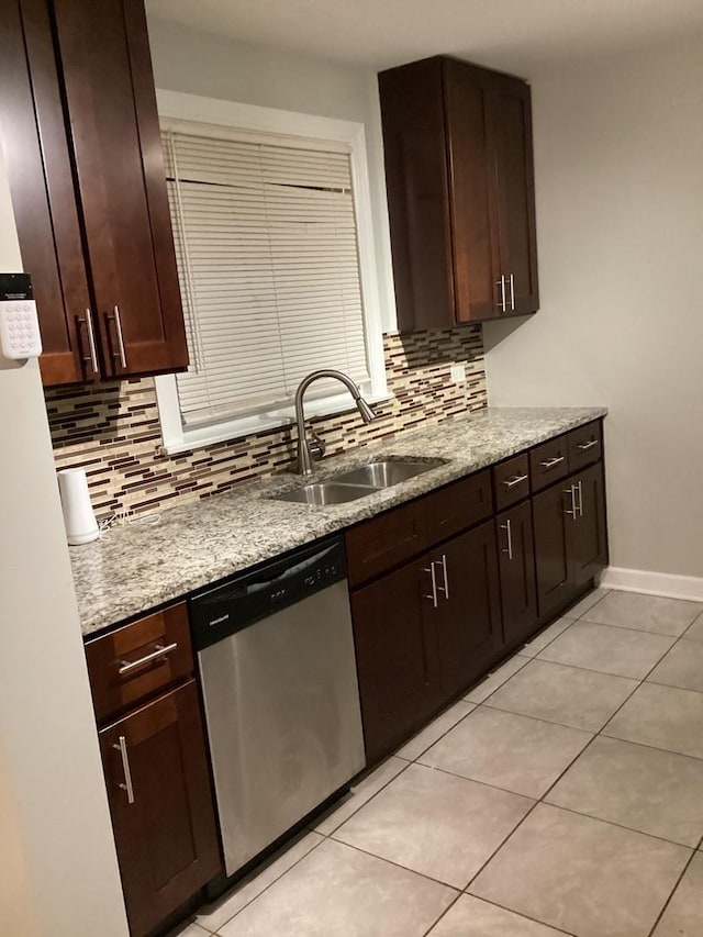 kitchen with light stone counters, dishwasher, sink, and dark brown cabinets