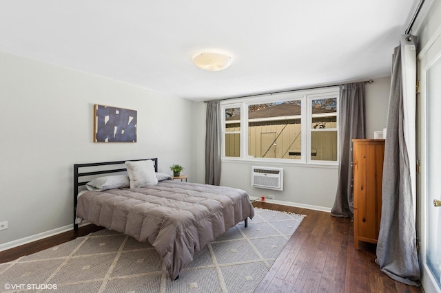 bedroom featuring a wall unit AC, baseboards, and hardwood / wood-style floors