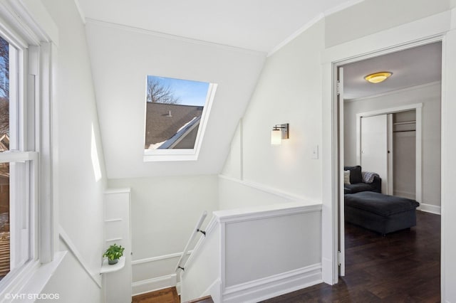 corridor with ornamental molding, wood finished floors, and baseboards