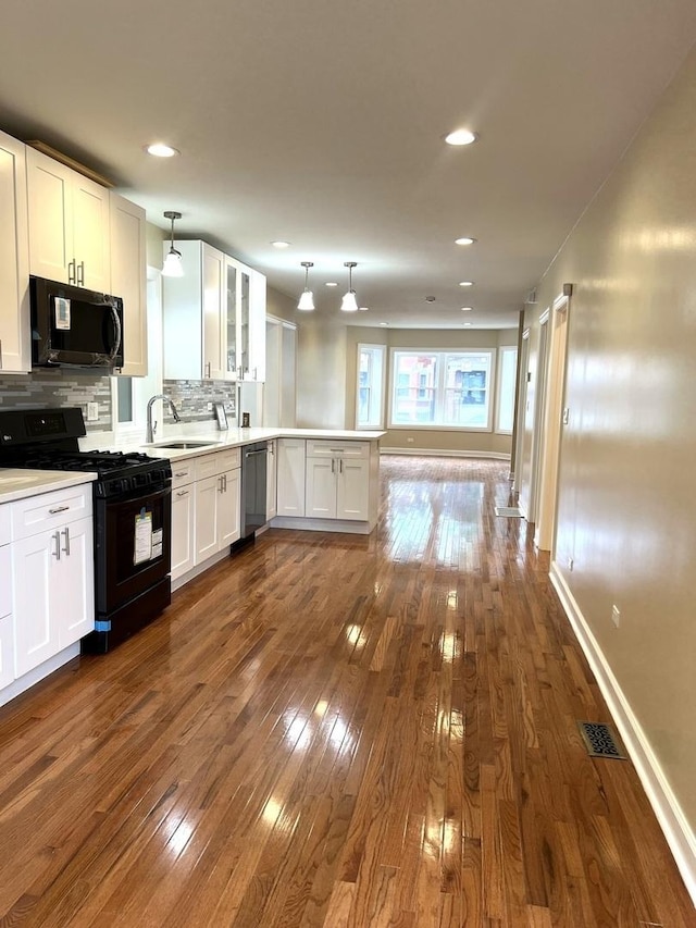 kitchen featuring white cabinetry, kitchen peninsula, backsplash, hanging light fixtures, and black range with gas cooktop