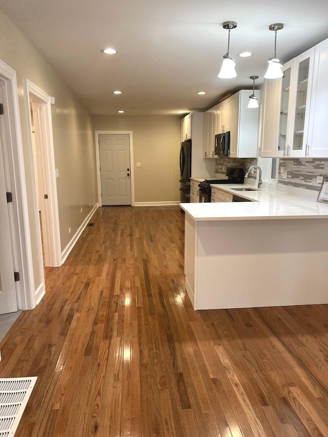 kitchen featuring white cabinets, black appliances, tasteful backsplash, sink, and kitchen peninsula