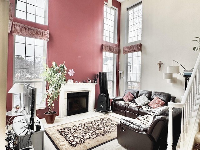 living room with a towering ceiling and a tiled fireplace