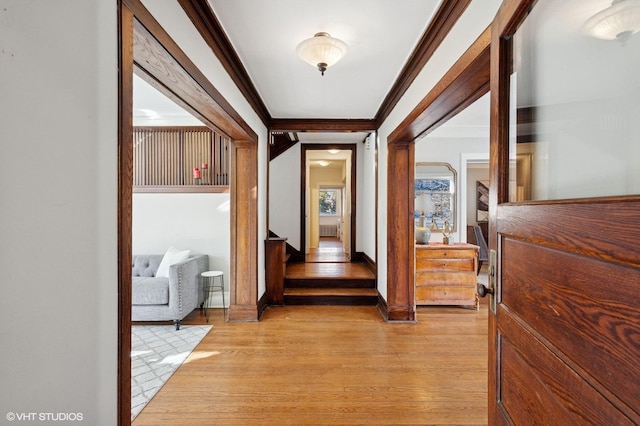 corridor featuring light wood-style flooring, ornamental molding, and baseboards