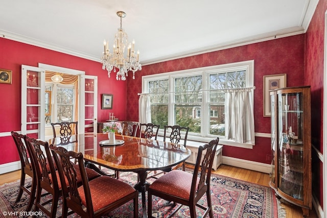 dining space featuring baseboards, a notable chandelier, wood finished floors, and crown molding