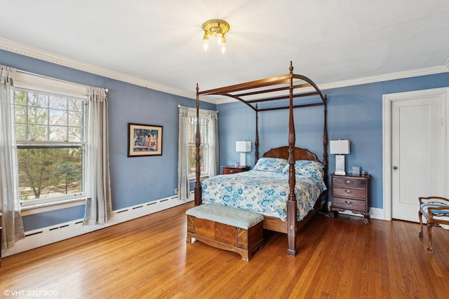 bedroom with baseboards, crown molding, baseboard heating, and wood finished floors