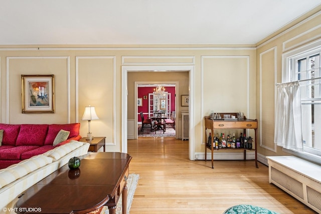 living area featuring plenty of natural light, a decorative wall, light wood finished floors, and radiator heating unit