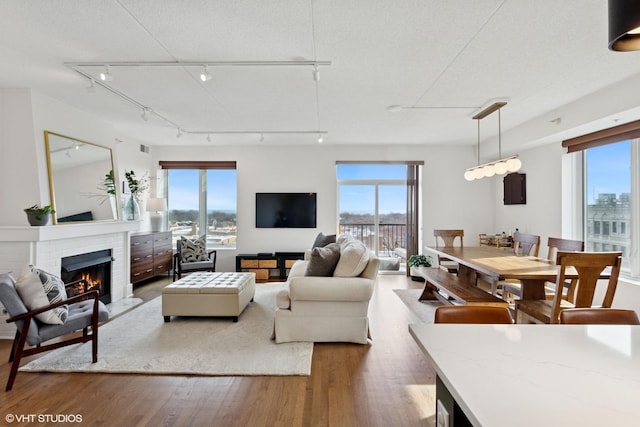 living room featuring a brick fireplace, a textured ceiling, and wood finished floors