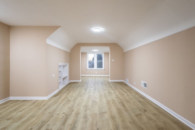 additional living space with light hardwood / wood-style flooring and lofted ceiling