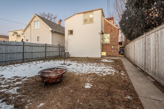 snow covered rear of property featuring a fire pit