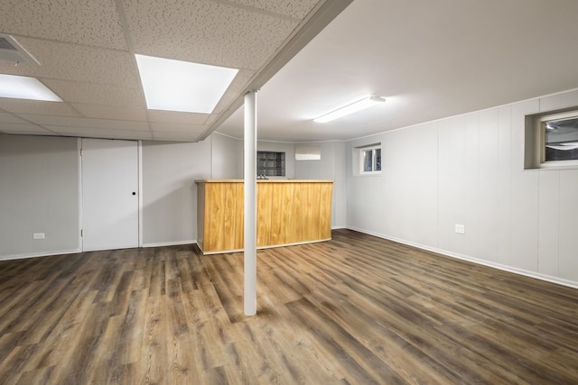 basement with dark wood-type flooring, a drop ceiling, and bar