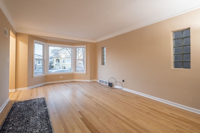 empty room with ornamental molding and light hardwood / wood-style flooring