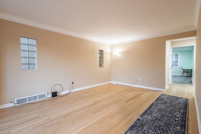 empty room with hardwood / wood-style floors and crown molding