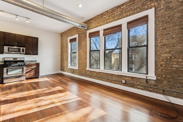 kitchen featuring hardwood / wood-style floors, appliances with stainless steel finishes, a wealth of natural light, and dark brown cabinetry