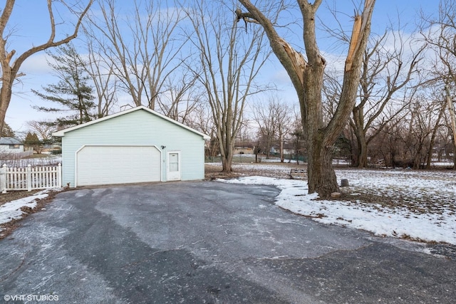 snow covered property featuring a garage and an outdoor structure