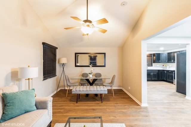 dining room with light wood-type flooring, vaulted ceiling, and ceiling fan