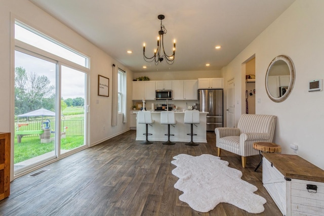 kitchen featuring appliances with stainless steel finishes, an island with sink, a breakfast bar area, white cabinets, and hanging light fixtures