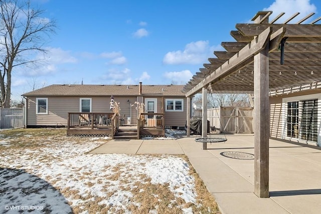 snow covered back of property with a pergola, a deck, and a patio