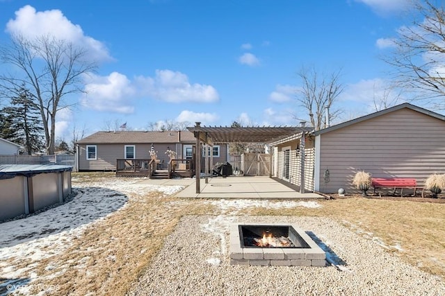 rear view of house with a pergola, a pool side deck, and an outdoor fire pit